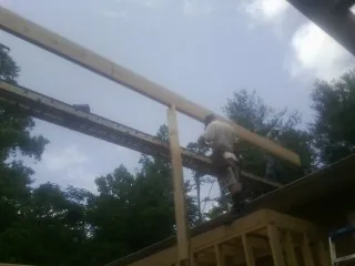 Carpenter setting a ridge beam over a new addition frame — Ice Dam Removal by Roofing Brothers in Mathews