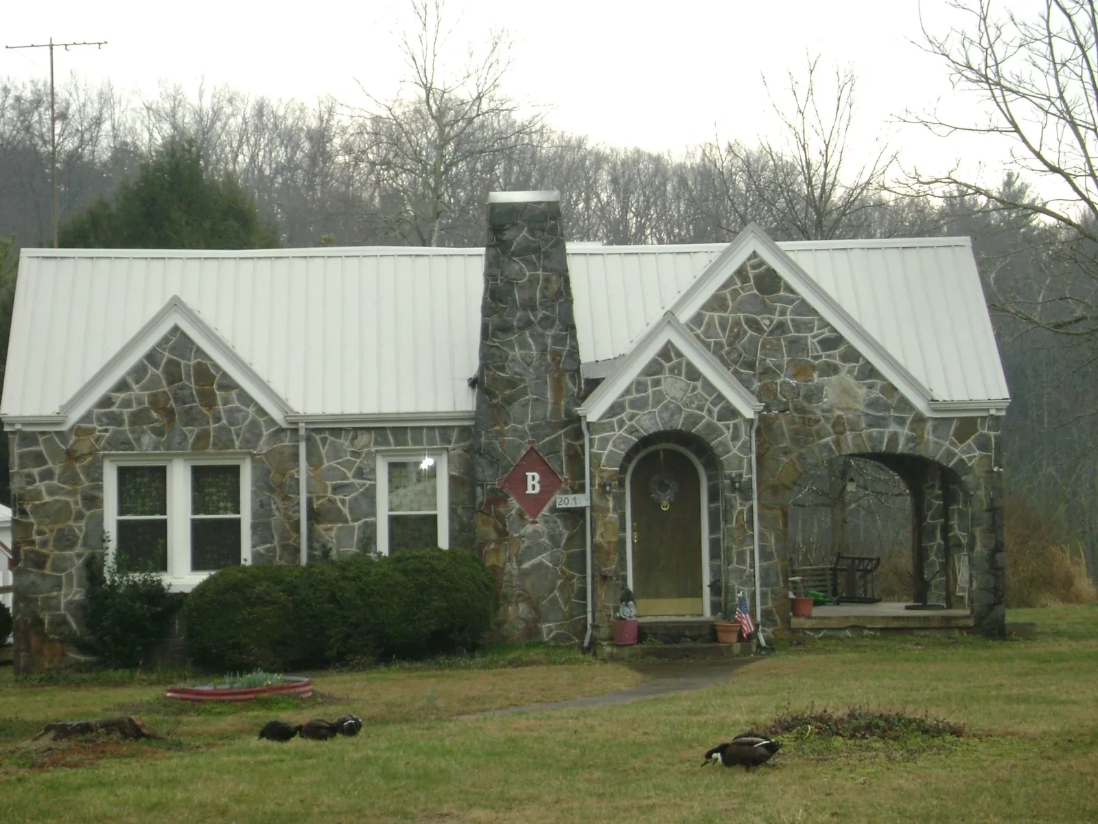White metal roof on a stone cottage with steep gables in Mathews