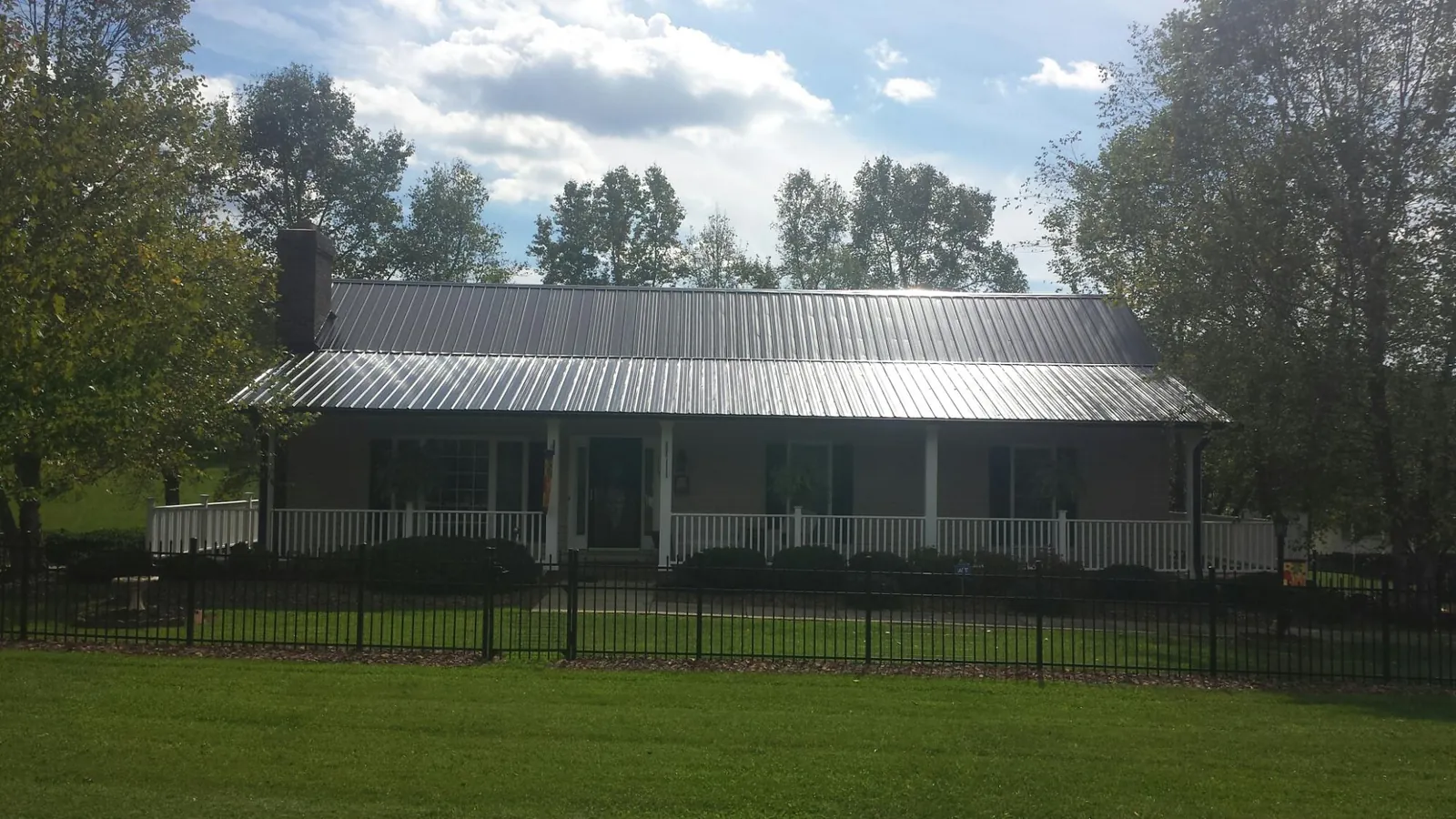 Gray metal roof on a brick ranch with a full width front porch — Gutter Guard Installation work by our crew in Mathews